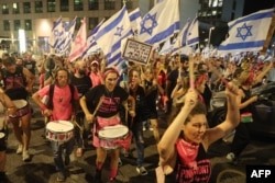 Protestuesit duke i valëvitur flamuj izraelitë gjatë protestës të enjten vonë në Tel Aviv, më 27 korrik 2023.