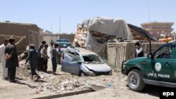 Afghan security officials inspect the site of a bomb blast that targeted a private vehicle of policemen, in Ghazni. (file photo)