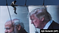 Працівник в місті Ахмадабад монтує величезний плакат із фотографією Дональда Трампа перед початком візиту президента США до Індії, 20 лютого 2020 року
