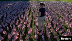 File photo a woman stands among some of the 3,000 flags placed in memory of the lives lost in the September 11, 2001 attacks, at a park in Winnetka, Illinois.