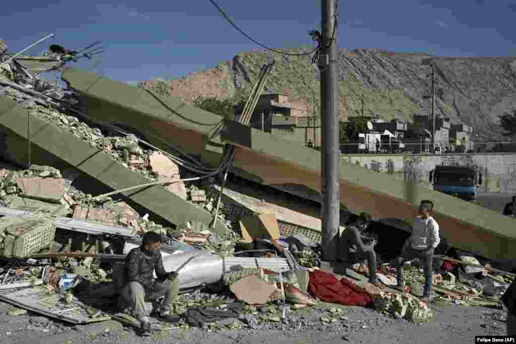 People sit on the rubble of a destroyed house in the city of Darbandikhan in northern Iraq.