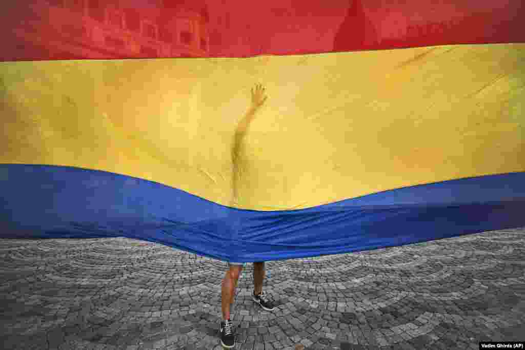 A youngster helps to unfurl a 100-meter-long national flag as Romanians celebrated National Anthem Day in Bucharest. (AP/Vadim Ghirda)