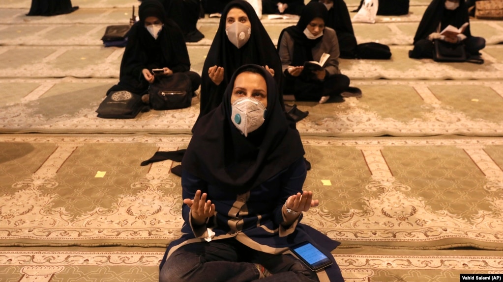Women wearing protective face masks pray at a Tehran mosque.