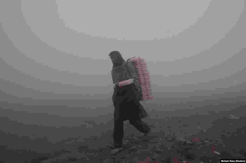 A vendor carries plastic boxes full of cake to sell on the streets on a smoggy morning in Lahore, Pakistan. (Reuters/Mohsin Raza)