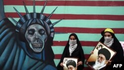 Women hold pictures of Supreme Leader Ayatollah Ali Khamenei outside the former U.S. Embassy in Tehran on November 4, marking the day in 1979 when protesters stormed the embassy and took 52 Americans hostage for over a year.