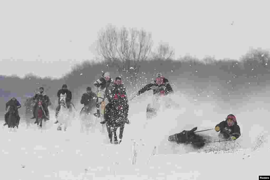 ცხენოსანთა შეჯიბრი რუმინეთში. Romania -- A horse and a rider fall in the snow during a race that followed the celebration of an Epiphany religious service, in Pietrosani, Prahova county, Romania January 6, 2017.