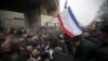 Men help pull one another out of a crushing stampede as a Crimean flag is waved near the regional parliament building in Simferopol on February 26.