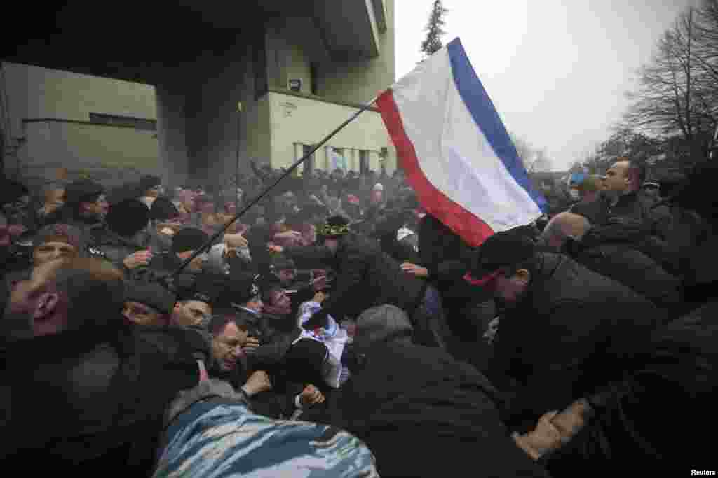 Men help pull one another out of a crushing stampede as a Crimean flag is waved near the regional parliament building in Simferopol on February 26.