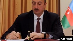İlham Əliyev sənəd imzalayır.