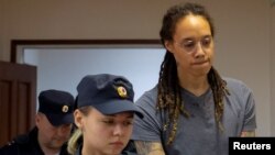 Brittney Griner amerikai kosárlabdázót (jobbra) elvezetik a Moszkva melletti Himkiben tartott bírósági tárgyalásról, miután kilenc év börtönre ítélték