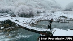 په پنجشېر کې یو افغان تر واورې ورېدو وروسته له پله تېرېږي - انځور له ارشیفه. 