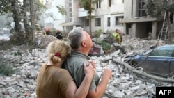 Ljudi stoje ispred djelimično uništene stambene zgrade usljed ruskih raketnih napada u zapadnom ukrajinskom gradu Lvivu 30. jula.