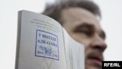 Анатоль Лябедзька трымае пашпарт, на якім стаіць пячатка “У выездзе адмоўлена” 