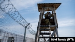 Egy katona távcsővel figyeli a határsávot az ideiglenes biztonsági határzár mellett a magyar-szerb határon, Bácsalmás közelében 2020. július 16-án.