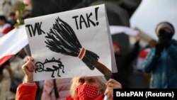 A woman holds a placard reading "Tick tock!" as she attends an opposition rally in Minsk on October 26.