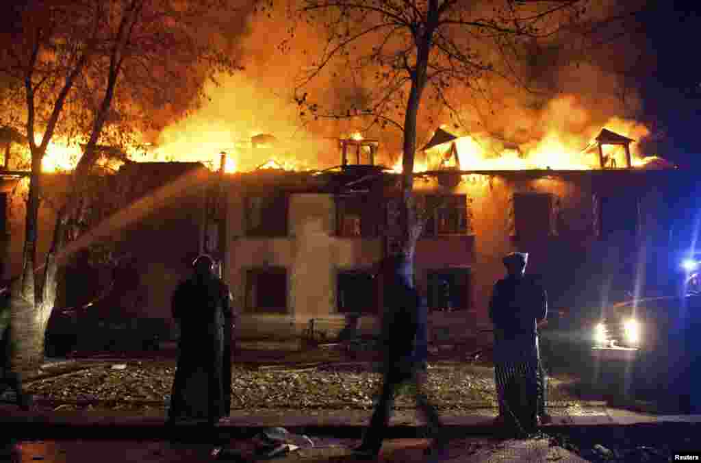 Azerbaijani riot police look on as firefighters (left, unseen) try to put out fires from a building after mass protests in the town of Ismayilli on January 24. (Reuters/Aziz Karimov)