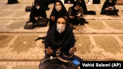 Women wearing protective face masks pray at a Tehran mosque.