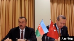 Azerbaijani President Ilham Aliyev (left) and Turkish Prime Minister Recep Tayyip Erdogan sign a protocol of the first meeting of Azerbaijan-Turkey High-Level Strategic Cooperation Council in Izmir on October 25.