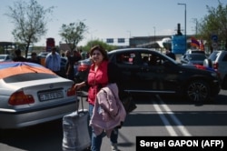 A woman walks with her suitcase past protesters blocking the road to the airport in Yerevan on May 2.