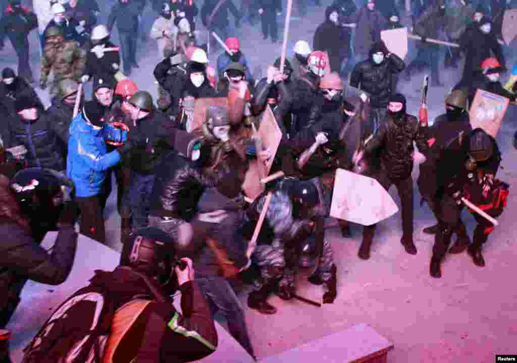 Pro-EU&nbsp;protesters clash with Ukrainian riot police during a rally near government administration buildings in Kyiv on January 19, 2014. Protesters attacked riot police with sticks and tried to overturn a bus blocking their path to parliament, as up to 100,000 Ukrainians massed in defiance of sweeping new laws aimed at stamping out antigovernment demonstrations.