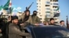 Anti-government fighters brandish their guns as they ride a vehicle in Syria's northern city of Aleppo on November 30, 2024.