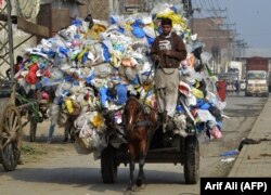 Таштандыга ыргытылган желим шишелерди ташып бараткан бала. Лахор, Пакистан.11-декабрь, 2018-жыл.