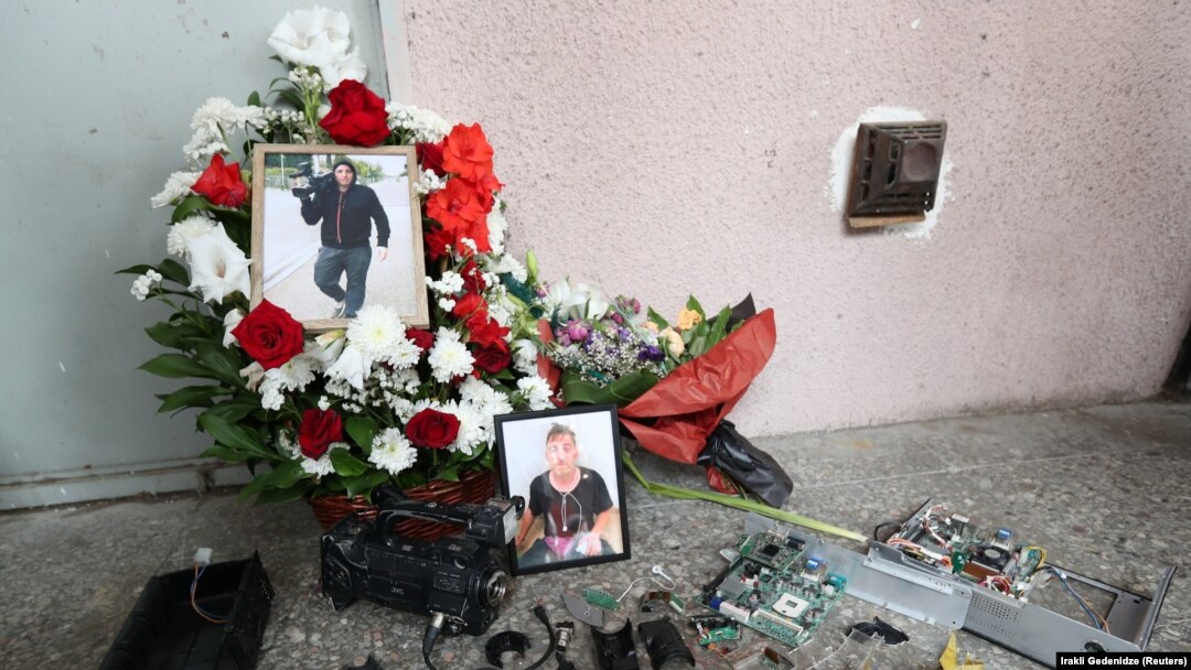 Portraits of TV cameraman Lekso Lashkarava are placed next to a broken camera during his funeral in Tbilisi on July 13.