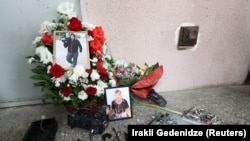 Portraits of TV cameraman Lekso Lashkarava are placed next to a broken camera during his funeral in Tbilisi on July 13.