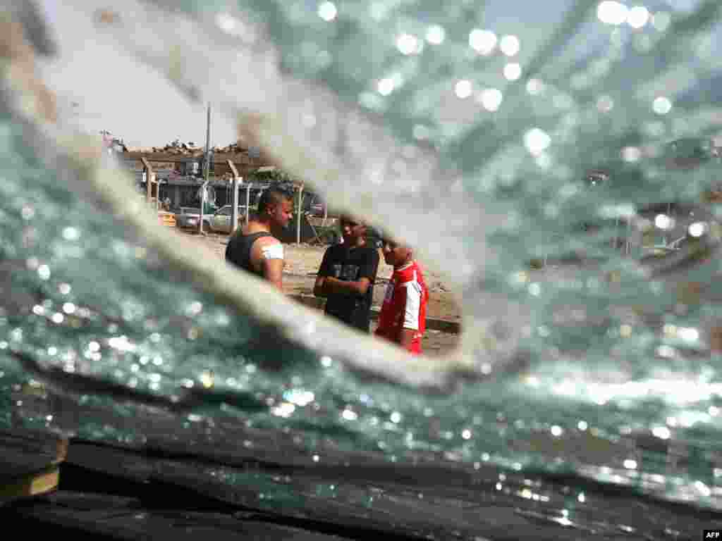 The shattered windscreen of a vehicle is seen as Iraqis gather along Al-Sheikh Omar Street in the center of Baghdad after two near-simultaneous roadside bombs detonated on September 8 ahead of the Muslim holiday of Eid al-Fitr. Two people were killed.Photo by Ali Al-Saadi for AFP