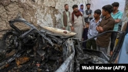 Afghan residents and family members of the victims on August 30 gather next to a damaged vehicle a day after a U.S. drone air strike in Kabul.