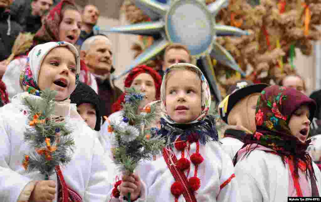 Ukrainians sing Christmas carols as they carry a decorated star of Bethlehem and sheaves of wheat during a Christmas parade in downtown Lviv on January 6. (EPA-EFE/Mykola Tys)