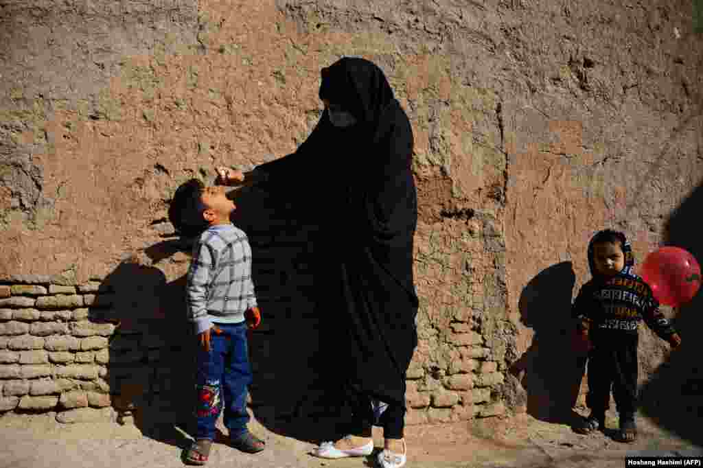 Një punëtore shëndetësore, e veshur me burka, i jep vaksinën për polio një fëmije në Herat të Afganistanit.(AFP/Hoshang Hashimi)