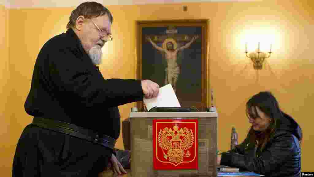 An Orthodox monk casts his ballot during the presidential elections at the Nilova Pustyn monastery near the town of Ostashkov