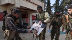 Members of Hayat Tahrir al-Sham set fire to a photo of ousted Syrian President Bashir al-Assad in Aleppo, northwestern Syria, on November 29.