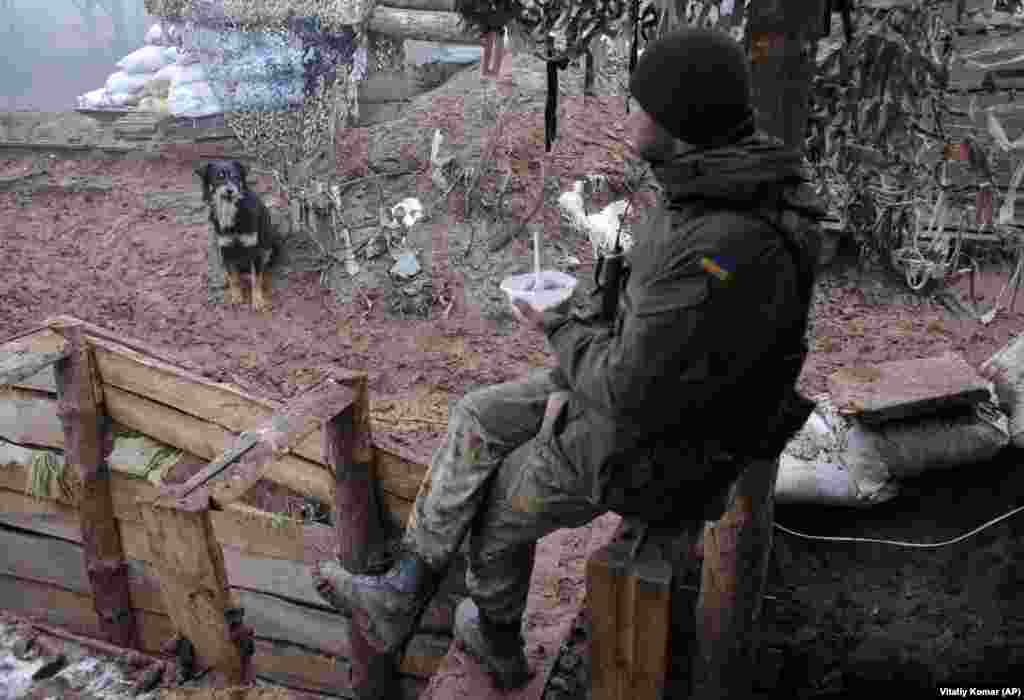 A Ukrainian soldier eats in a trench on the front line near the town of Novoluhanske in the Donetsk region. (AP/Vitaliy Komar)