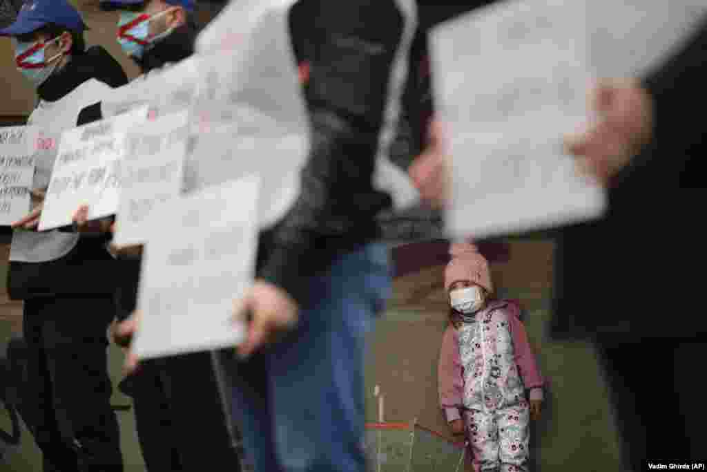 A little girl stands behind police officers protesting in Bucharest on March 1. Dozens of Romanian police gathered outside the Labor and Social Protection Ministry to protest planned austerity measures that envisage freezing the salaries of public-sector workers. (AP/Vadim Ghirda)