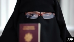 A Muslim woman wearing the niqab shows her passport in Montreuil, outside Paris.