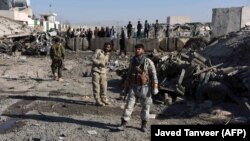 Afghan security personnel gather at the site of a suicide attack at a police compound in Maiwand district of Kandahar Province in late December.