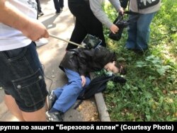 Жительница района лежит на земле после того, как ее толкнул полицейский