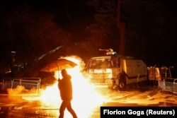 Një person kalon pranë vendit ku protestuesit hodhën koktej molotovi në Tiranë.