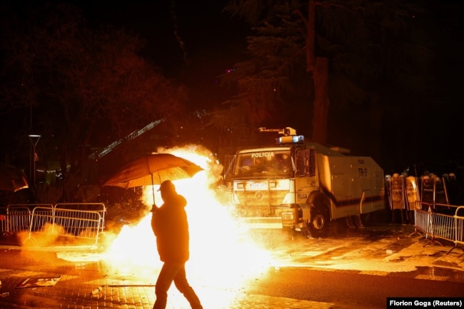 Një person kalon pranë vendit ku protestuesit hodhën koktej molotovi në Tiranë.