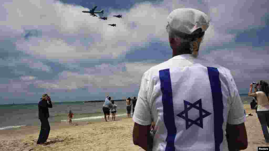 Bystanders look on as Israeli Air Force jets fly in formation over the Mediterranean Sea near Tel Aviv during celebrations for Israel&#39;s Independence Day marking the 64th anniversary of the creation of the state on April 26. (Reuters/Nir Elias)