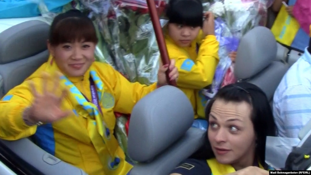 Kazakh weightlifters Maiya Maneza (left), Zulfiya Chinshanlo (center), and Svetlana Podobedova (right) are welcomed at Almaty airport in August 2012.