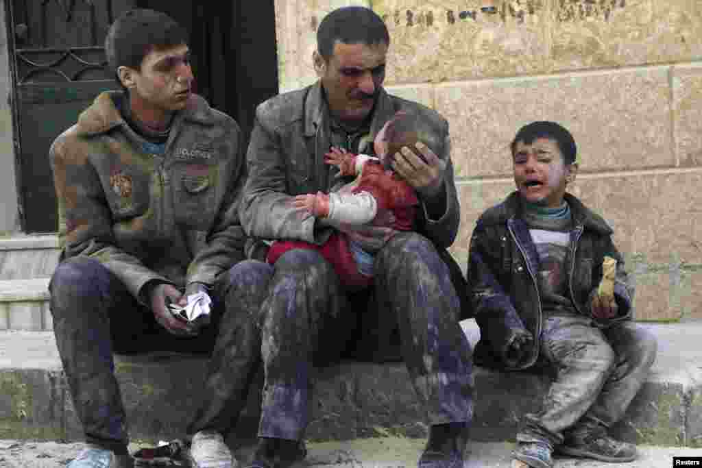 A man holds a baby saved from under rubble after what activists say was an air strike by Syrian government forces in Masaken Hanano in Aleppo on February 14. (Reuters/Hosam Katan)