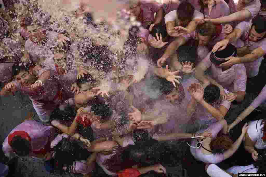 Revelers cool down as water is poured on them from people on balconies during the launch of the Chupinazo rocket to celebrate the official opening of the 2018 San Fermin festival in Pamplona, Spain. (AP/Alvaro Barrientos)
