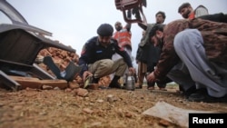 A policeman, rescue workers, and security officials collect evidence from the site of a bomb attack in western Pakistan in January.