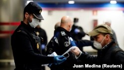 Իսպանիա - Ոստիկանները Մադրիդի մետրոյի կայարաններից մեկի մուտքի մոտ պաշտպանիչ դիմակներ են բաժանում, 13-ը ապրիլի, 2020թ.
