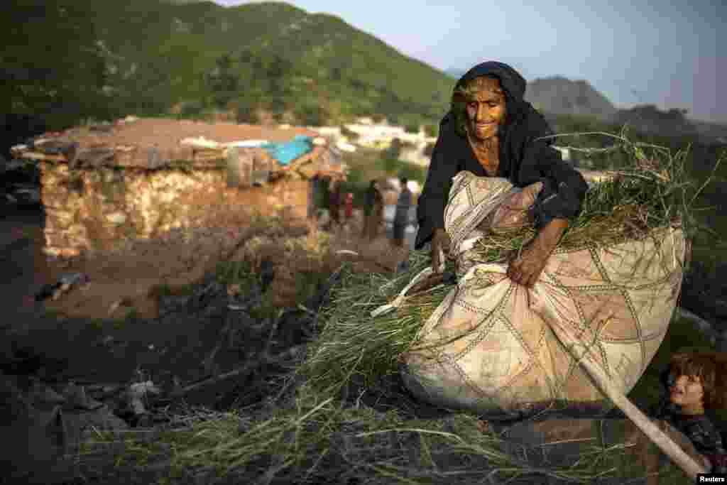 A woman whose family moved to Islamabad from Pakistan's Khyber-Pakhtunkhwa province to look for work tries to open a sack of grass and hay for her cattle on the outskirts of Islamabad. (Reuters/Zohra Bensemra)