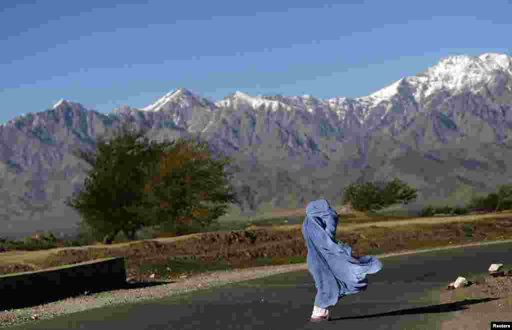 A woman in a burqa walks along a road on a windy day on the outskirts of Kabul. (Reuters/Mohammad Ismail)