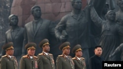 Kim Jong-un (right) stands with military officers during the unveiling ceremony of bronze statues of his father and grandfather on April 13 in Pyongyang.